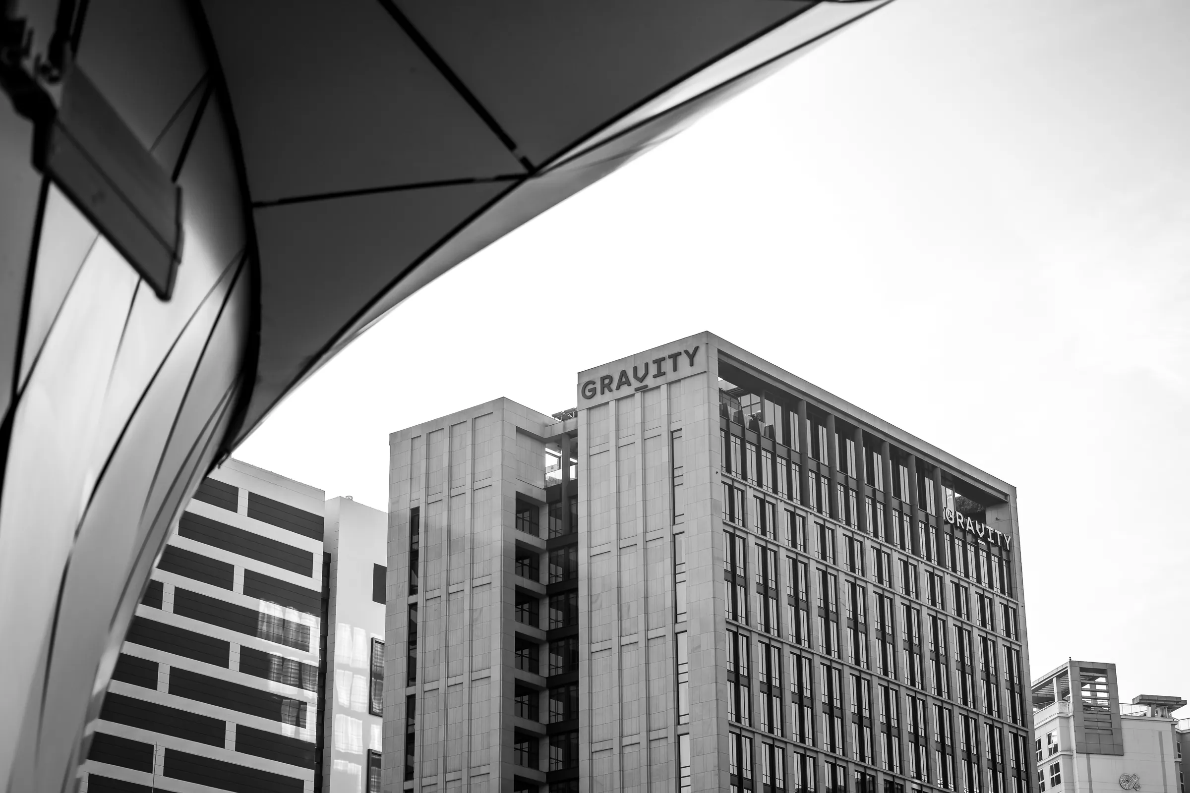 Black-and-white study of a curving white canopy sweeping over the corner of an office tower.