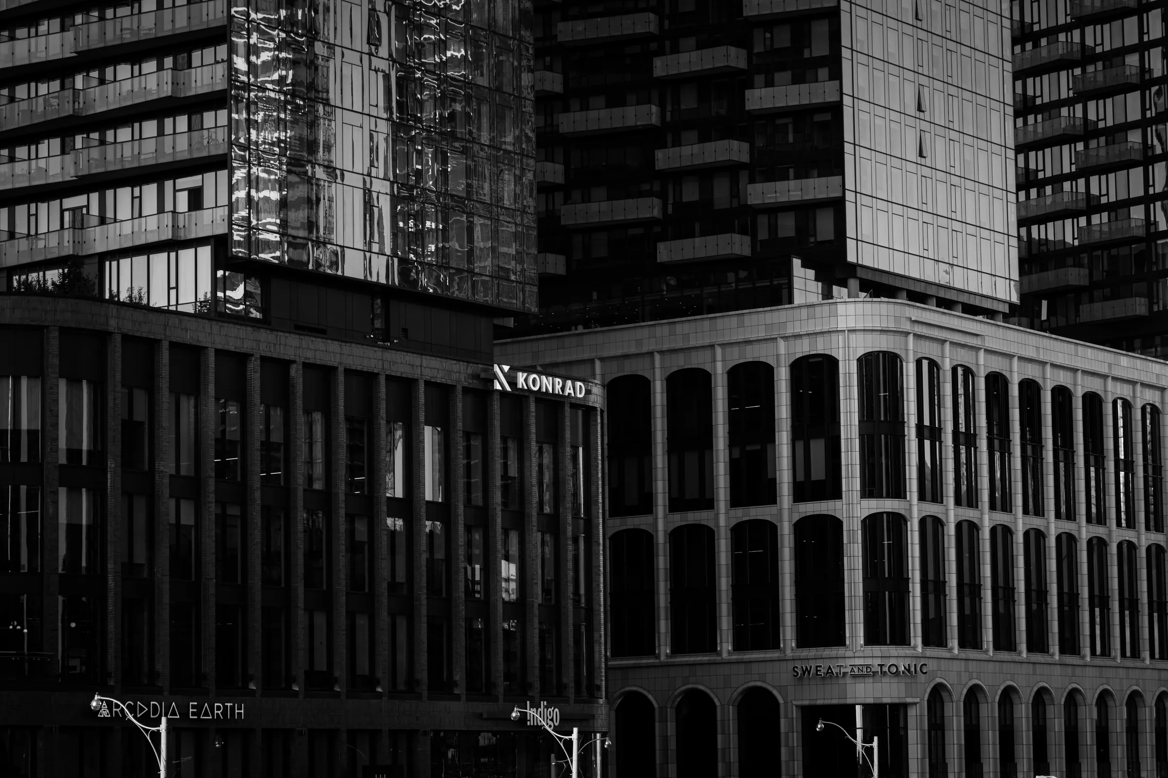 Black-and-white view of downtown towers: a glass condo tower reflecting its neighbours above an older stone building lined with arched windows.