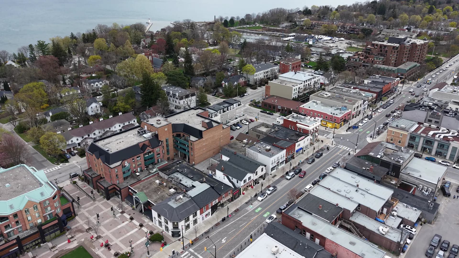 Drone view over downtown rooftops, parking lots and an intersection on an overcast day.